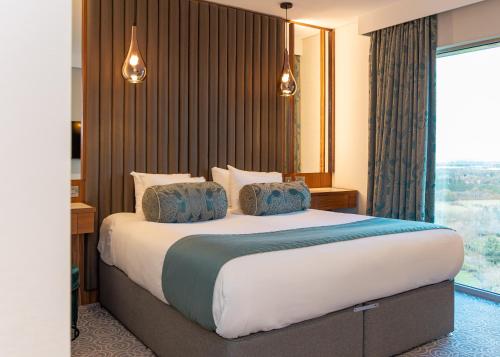 a bedroom with a large bed with a large window at Hotel La Tour in Milton Keynes