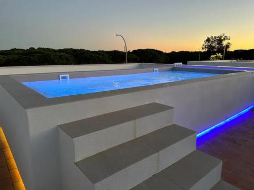 ein Pool mit blauen Lichtern an einem Gebäude in der Unterkunft VILLA MARIAH Barrosa Playa in Novo Sancti Petri