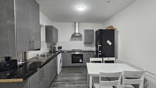 a kitchen with a table and a black refrigerator at Double Bedroom with private bathroom and shared kitchen in Oldbury