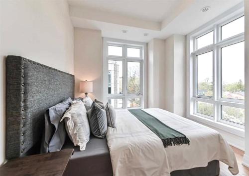 a bedroom with a large bed and two windows at Luxe Toronto Townhome, Rooftop Terrace, Parking in Toronto