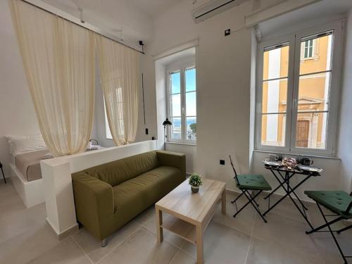 a living room with a green couch and two windows at Fouli,Syros Apartment,Ermoupoli in Ermoupoli