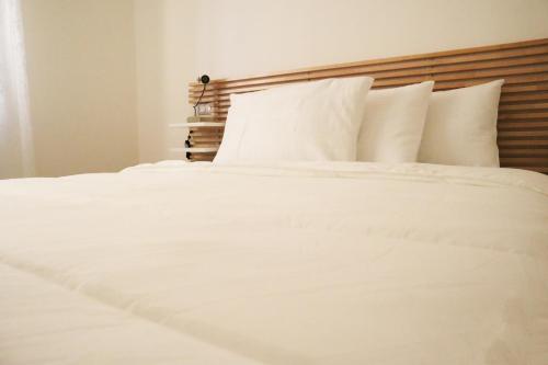 Cama blanca con sábanas y almohadas blancas en Corsico Comfort Home en Corsico