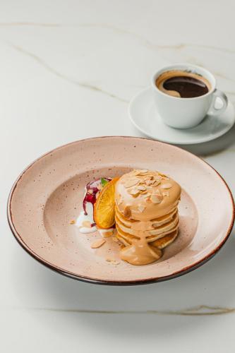 a plate of pancakes and a cup of coffee at Modern Art Hotel in Lviv