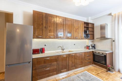 a kitchen with wooden cabinets and a stainless steel refrigerator at King George 32 Luxury Apartment in Thessaloniki