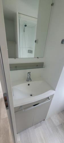 ein weißes Badezimmer mit einem Waschbecken und einem Spiegel in der Unterkunft Camping le Neptune 4 étoiles in Argelès-sur-Mer
