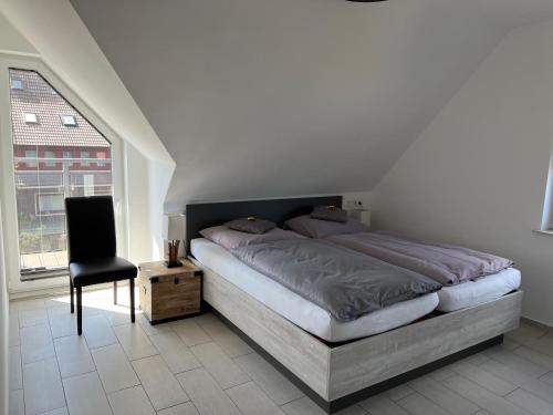 a bedroom with a bed and a chair and a window at Strandhaus Rose Apartement 32 in Juist