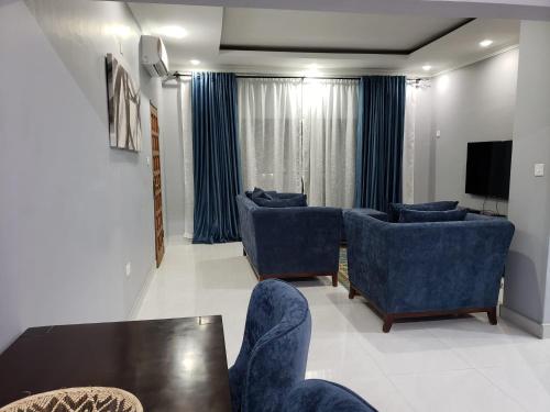 sala de estar con sillas azules y mesa en The KWASU Apartments, en Chipata