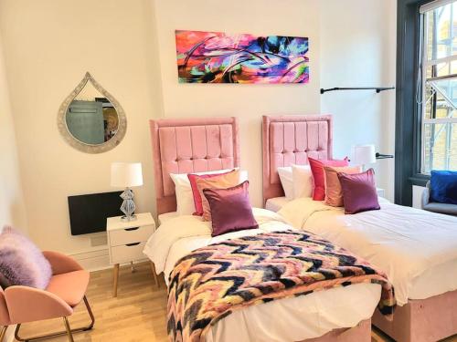 a bedroom with two beds and a mirror and a tv at Sensational Room Stays- Callcott Road in London