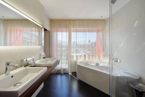a bathroom with two sinks and a tub and a shower at Hotel Du Nord in Interlaken