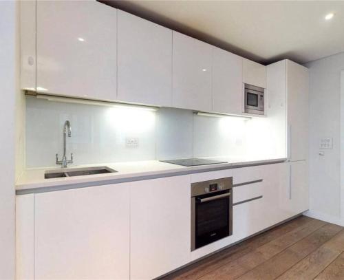 a white kitchen with white cabinets and a sink at Big & Relaxing House Near Spitafields Market in London