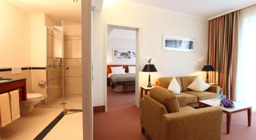 ein Hotelzimmer mit einem Sofa und einem Schlafzimmer in der Unterkunft ATLANTIC Hotel Wilhelmshaven in Wilhelmshaven