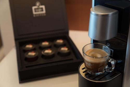 a cup of coffee sitting next to a coffee maker at ATLANTIC Hotel Wilhelmshaven in Wilhelmshaven