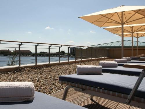 a row of beds on a deck with an umbrella at ATLANTIC Hotel Wilhelmshaven in Wilhelmshaven