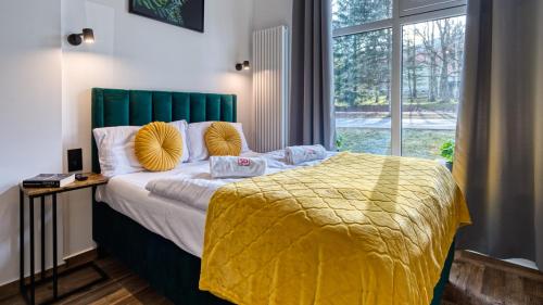 een slaapkamer met een groot bed en een gele deken bij Apartament Luxury 3 sypialnie, Sauna i Klimatyzacja - 5D Apartamenty in Świeradów-Zdrój
