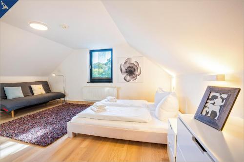 a white bedroom with a bed and a couch at Ferienhaus Wilde Wiese in Sellin