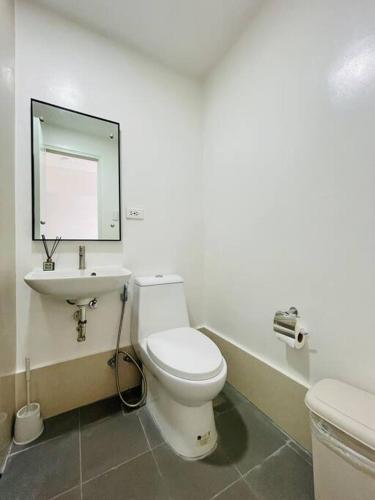 ein Badezimmer mit einem weißen WC und einem Waschbecken in der Unterkunft * * WV 2 Tranquil Haven in Iloilo City