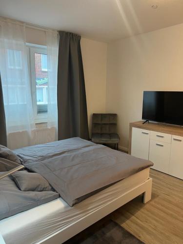 1 dormitorio con 1 cama y TV de pantalla plana en Haus Monika, en Juist