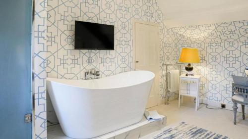 a bathroom with a tub and a tv on a wall at Aspen Suite in Barry