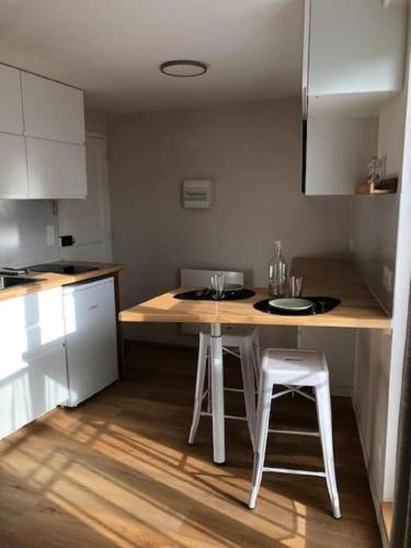 une cuisine avec une table et deux tabourets blancs dans l'établissement L'appart des Halles Tours centre, à Tours