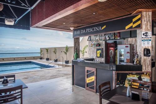 a bar at a resort with a swimming pool at Sol Victoria Marina Flat in Salvador