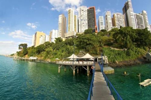 a pier in the water with a city in the background at Sol Victoria Marina Flat in Salvador