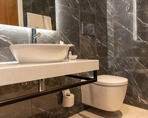 a bathroom with a sink and a toilet at Hotel La Tour in Milton Keynes