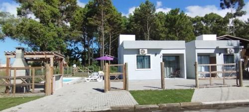 una pequeña casa blanca con piscina en Morada do bosque en Capão da Canoa