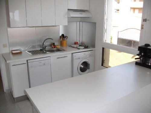 une cuisine blanche avec un évier et une machine à laver dans l'établissement Beau 2 pièces proche plage et vue mer, à Cavalaire-sur-Mer