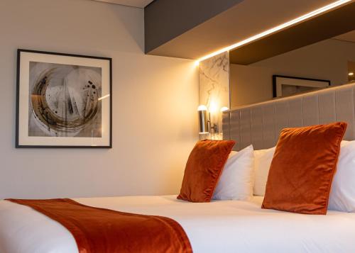 a hotel room with a bed with orange pillows at Hotel La Tour in Milton Keynes