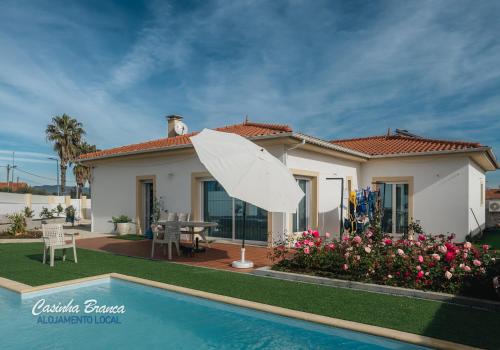 a house with a white umbrella in front of a swimming pool at Casinha Branca in Fundão