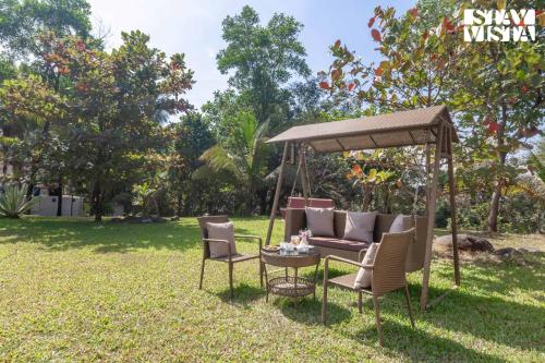 a gazebo with chairs and a table in a yard at StayVista's Firefly Mountain Retreat - Villa with Private Pool, Gazebo & Terrace in Karjat
