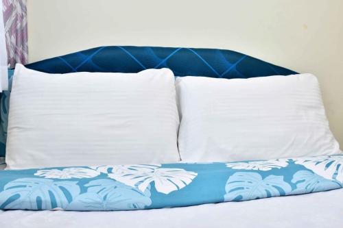 two white pillows and a blue and white blanket on a bed at Kandiz Exquisite in Nairobi