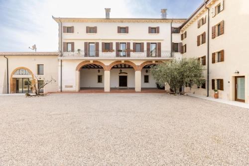 a large white building with a large driveway at VerdeOlivo 1876 - Apartments & Pool in Mezzane di Sotto