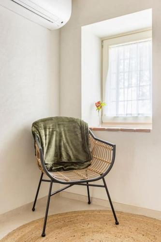 a chair with a green blanket sitting in a room at VerdeOlivo 1876 - Apartments & Pool in Mezzane di Sotto