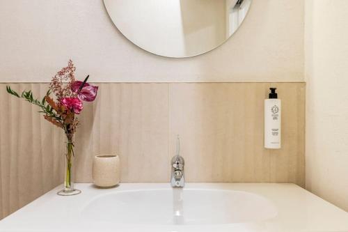 a bathroom sink with a vase of flowers and a mirror at VerdeOlivo 1876 - Apartments & Pool in Mezzane di Sotto