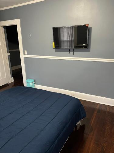 a bedroom with a bed and a flat screen tv on the wall at Cozy Room in Private Home in Irvington