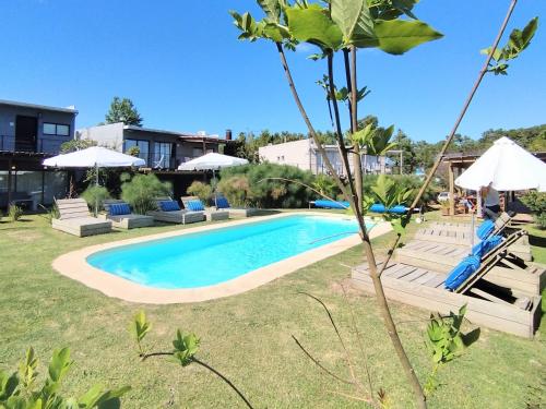 a swimming pool in a yard with chairs and umbrellas at La Bonita Suites Punta Colorada in Punta Colorada