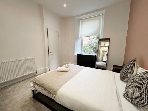 een slaapkamer met een groot wit bed en een raam bij Cosy Glasgow Retreat with Modern Amenities in Glasgow