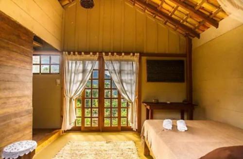 a bedroom with a bed and a table and a window at Refúgio Farm House in Paraty