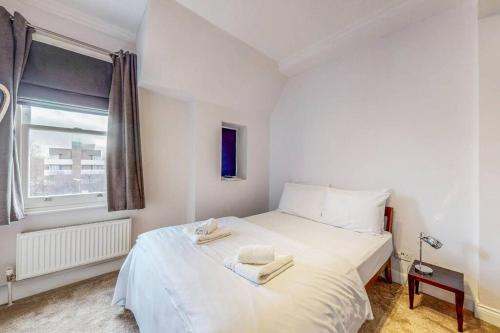 a white bed in a room with a window at Modern 1BD flat in Clapham Old Town in London