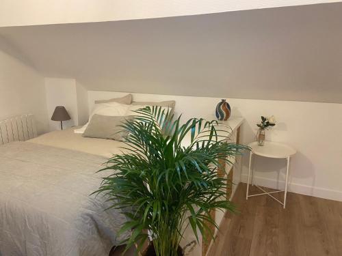 a bedroom with a bed and a table with a plant at La Mansarde LCD Pontoise in Pontoise