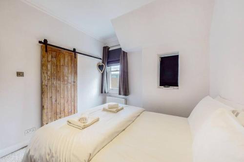 a white bedroom with a bed with two towels on it at Modern 1BD flat in Clapham Old Town in London