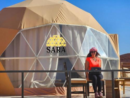 Una donna seduta davanti a una tenda di SARA LUXURY RUM CAMp a Wadi Rum