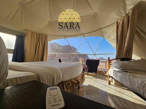 two beds in a tent with a view of the desert at SARA LUXURY RUM CAMp in Wadi Rum