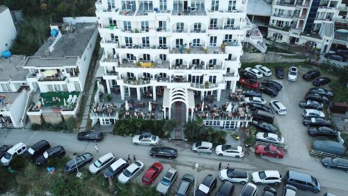 um grande edifício branco com carros estacionados num parque de estacionamento em Mona em Ulcinj