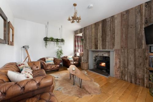 a living room with leather couches and a fireplace at Jacobite Lodge by The House of Danu in Kingussie