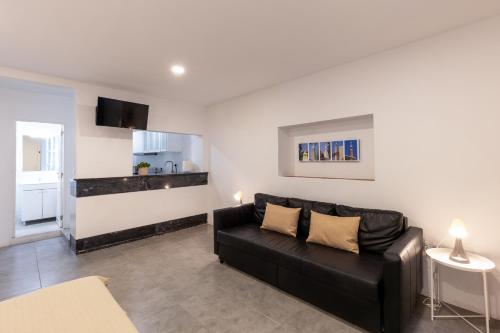 un salon avec un canapé noir et une cuisine dans l'établissement Faro Downtown Ria Formosa Studios, à Faro