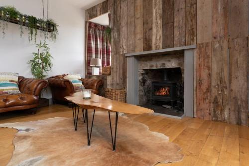 a living room with a table and a fireplace at Jacobite Lodge by The House of Danu in Kingussie
