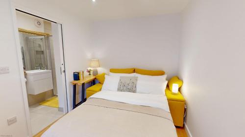 - une petite chambre avec un lit et une chaise jaune dans l'établissement The Conifer Studio, à Oxford
