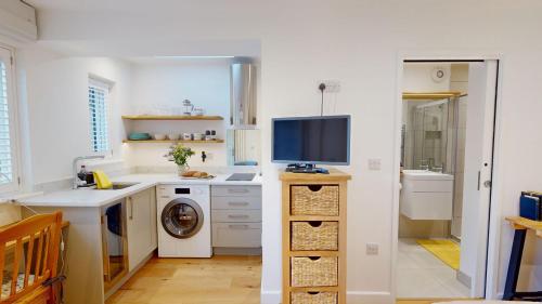 a kitchen with a washing machine and a tv on a counter at The Conifer Studio in Oxford
